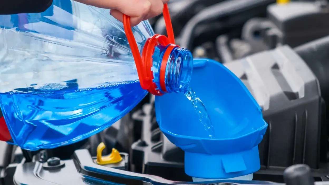 Líquido azul a ser despejado num funil no motor de um carro