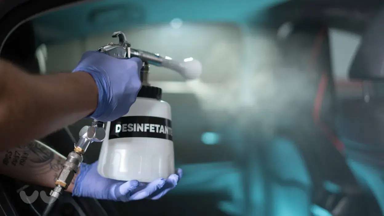 Pessoa a pulverizar desinfetante no interior de um carro usando equipamento especializado