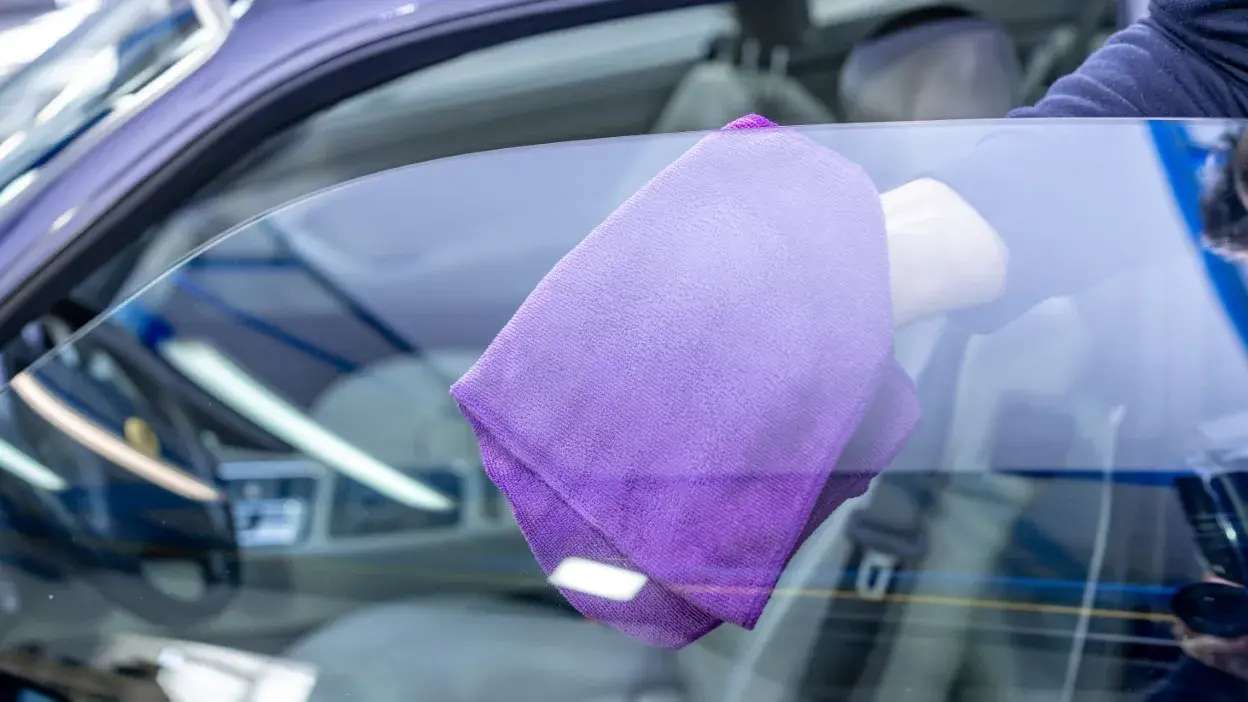 Pessoa a limpar vidro lateral de carro com pano