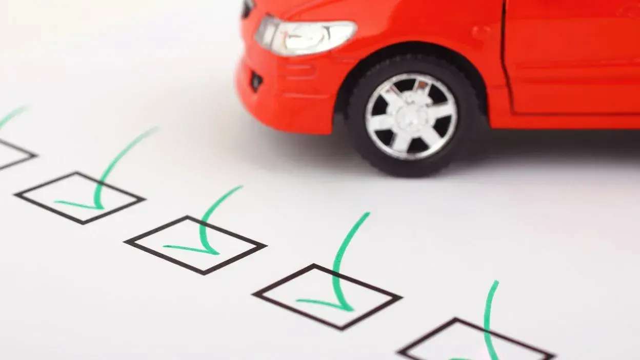 Carro vermelho sobre lista de verificação com caixas assinaladas em verde