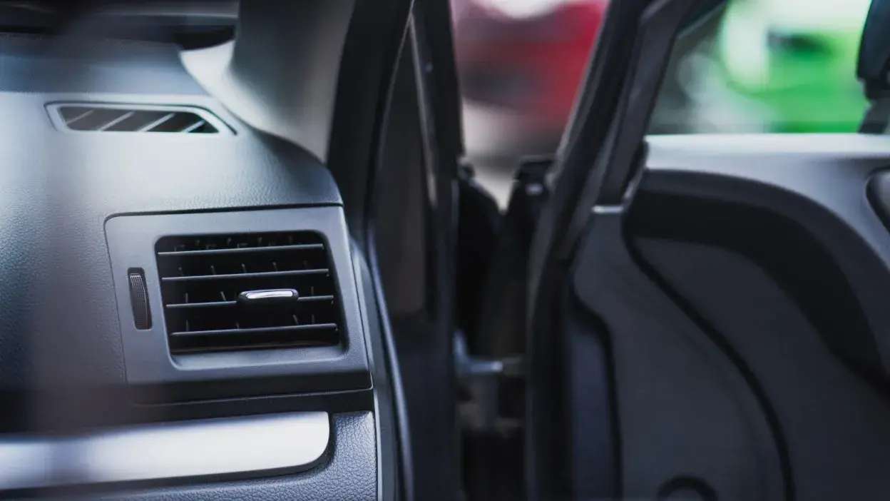 Grelha de ventilação do ar condicionado no interior de um carro, vista lateral.