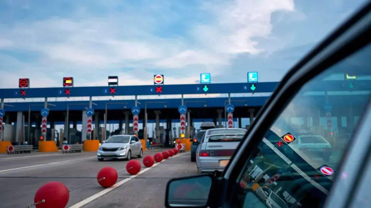Carros em fila para passar numa portagem com algumas vias fechadas e outras abertas