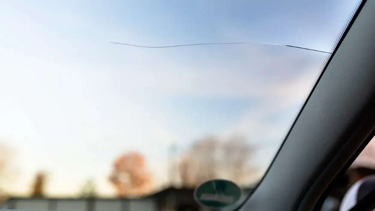 Para-brisas de carro com risco visível no vidro, vista interior do veículo.