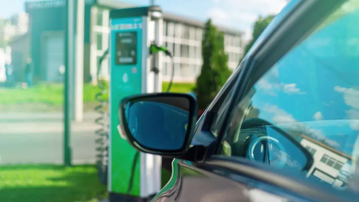 Carro elétrico ligado a posto de carregamento verde ao ar livre