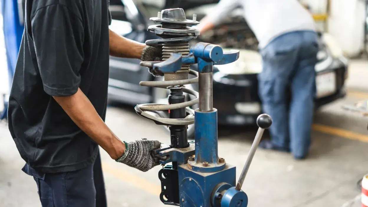 Técnico a montar um amortecedor com mola numa oficina automóvel