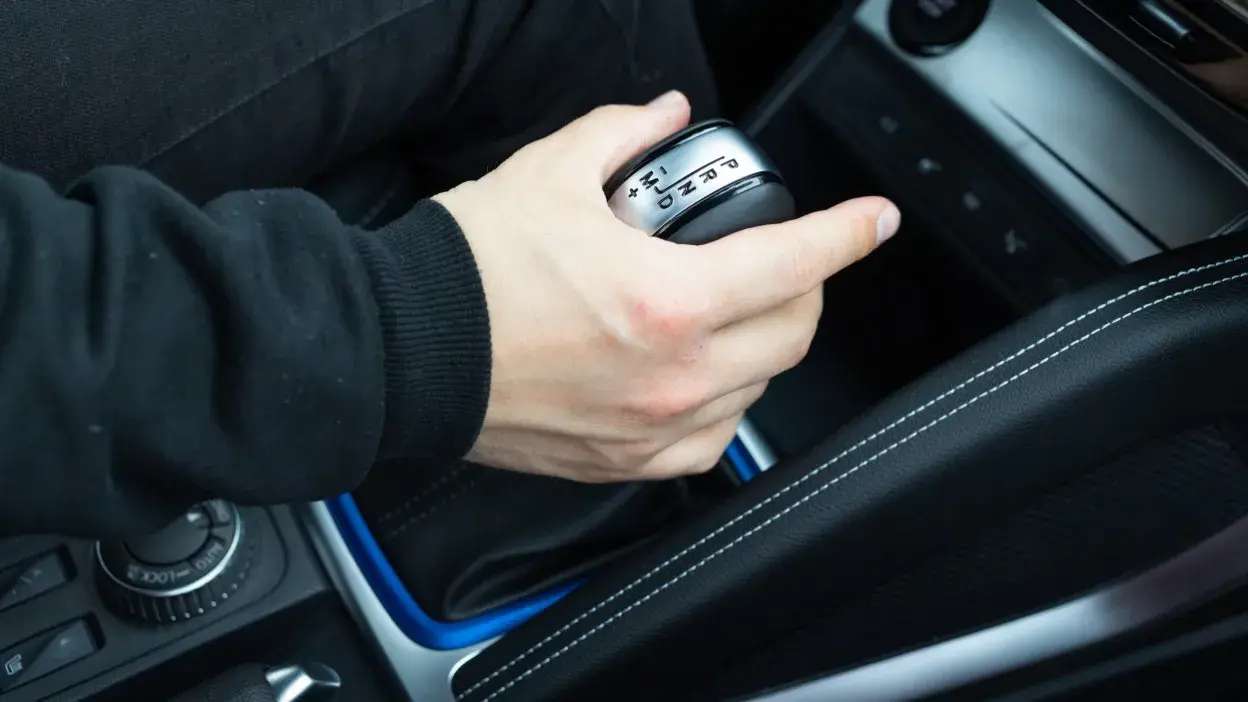 Mão a segurar a alavanca de mudanças de um carro automático.