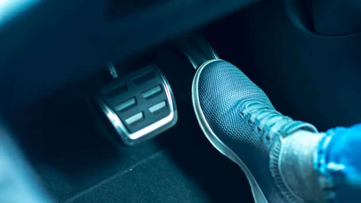 Pé com sapatilha a pressionar o pedal do acelerador de um carro automático.