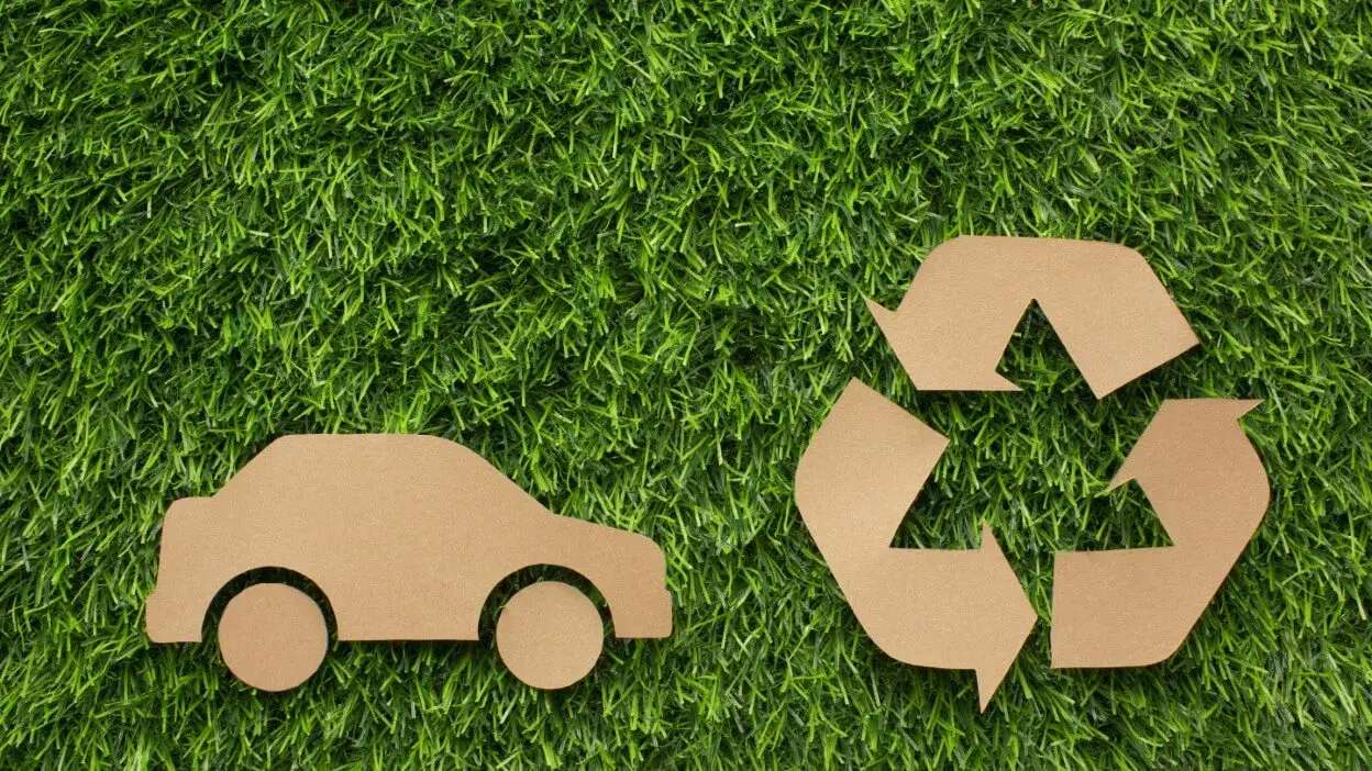 Símbolos de carro e reciclagem em cartão sobre relva verde