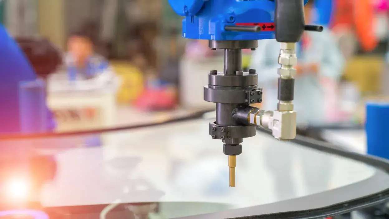 Máquina industrial a trabalhar vidro para automóvel numa linha de produção