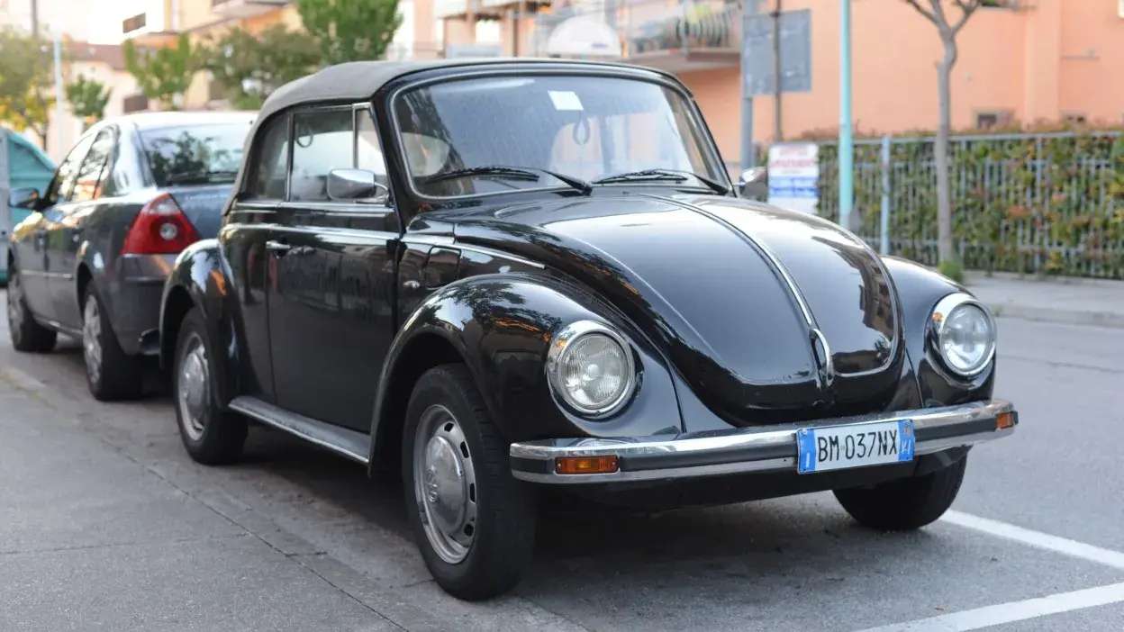 Carro clássico preto estacionado na rua com outros carros ao fundo