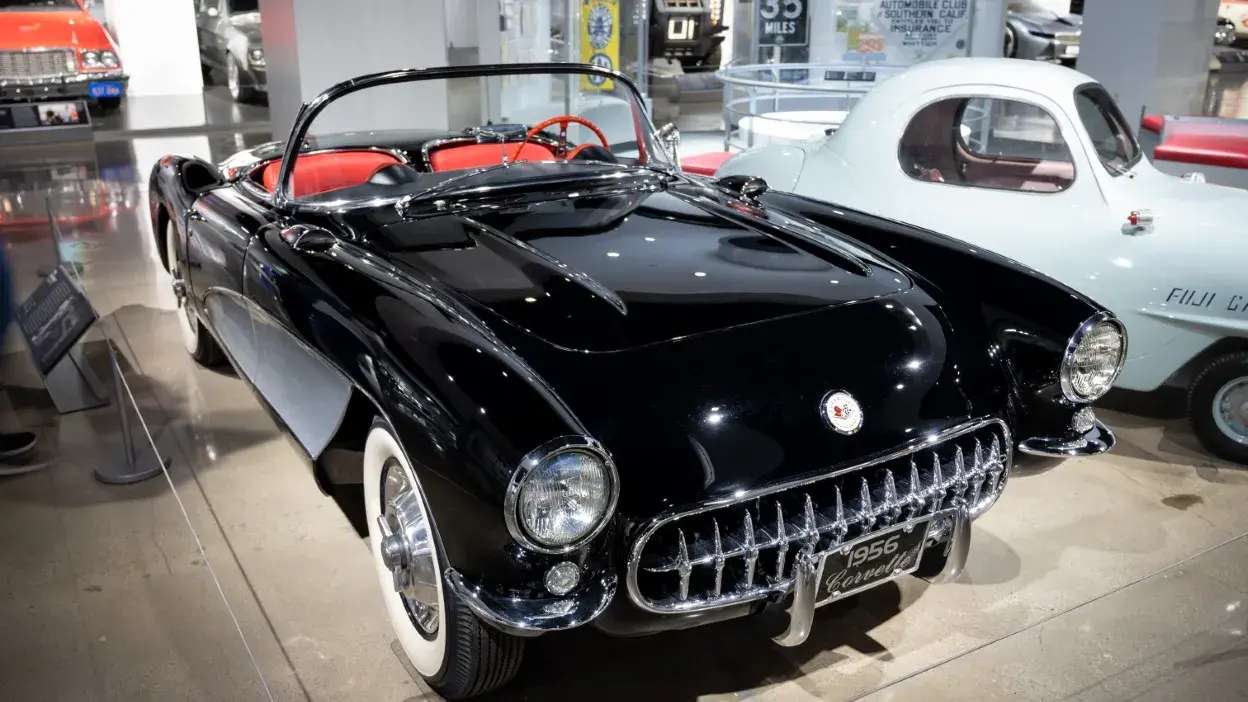 Automóvel clássico preto conversível com interior vermelho em exposição num museu.