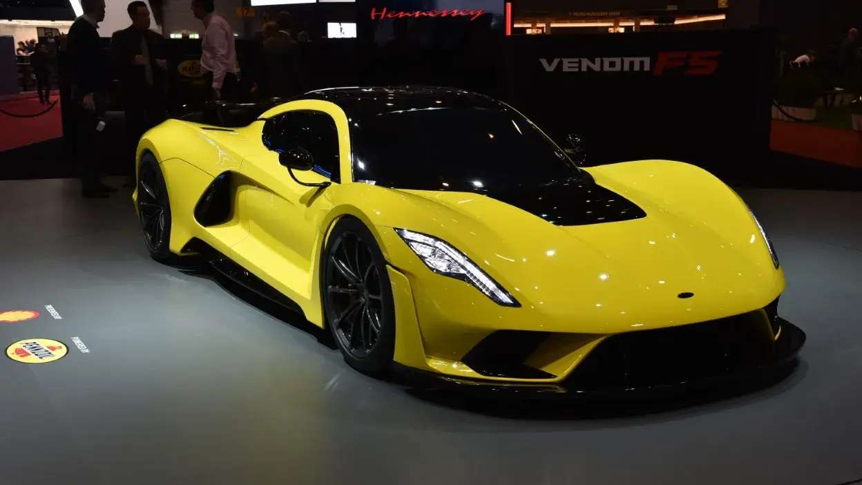 Carro desportivo amarelo com detalhes pretos exposto em salão automóvel.