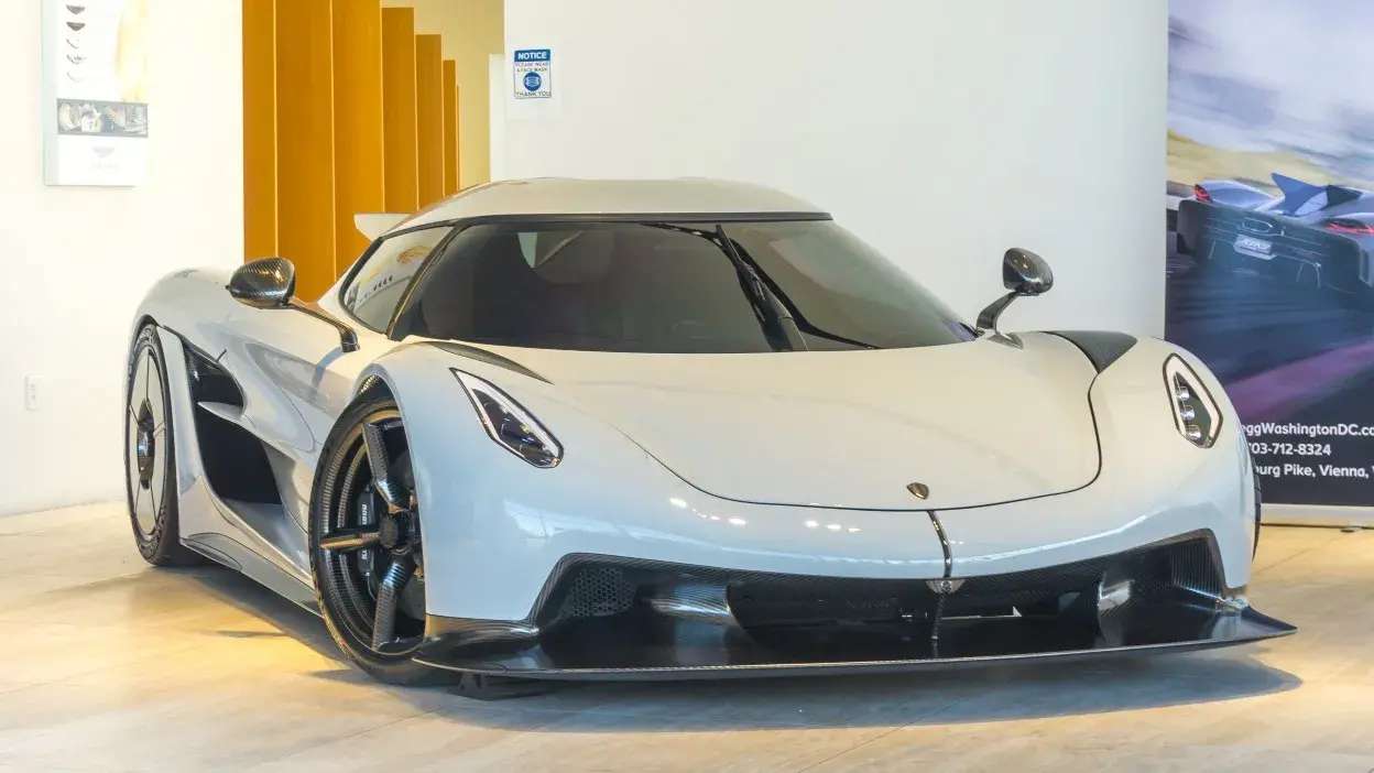 Carro desportivo branco estacionado em interior com design aerodinâmico e jantes pretas.