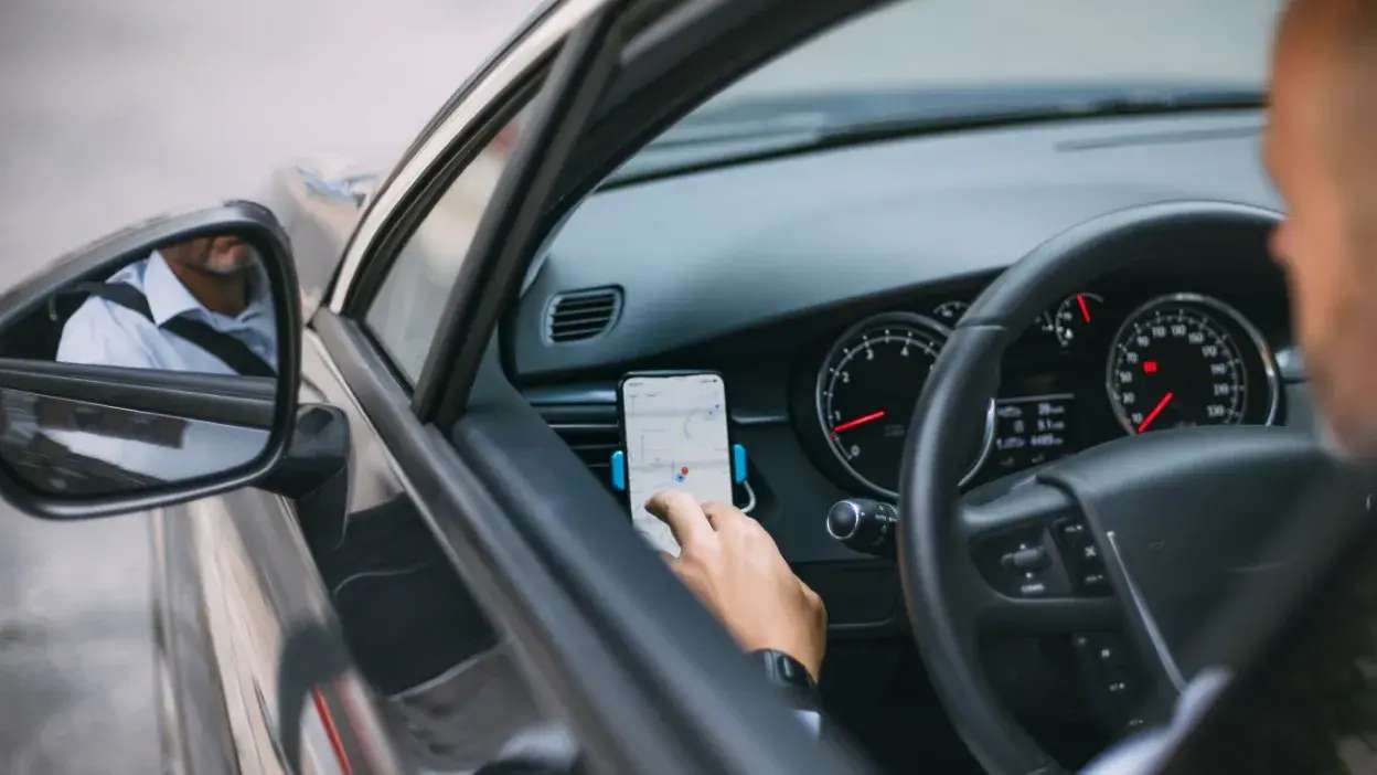Pessoa a usar aplicação de mapas num smartphone dentro de um carro.