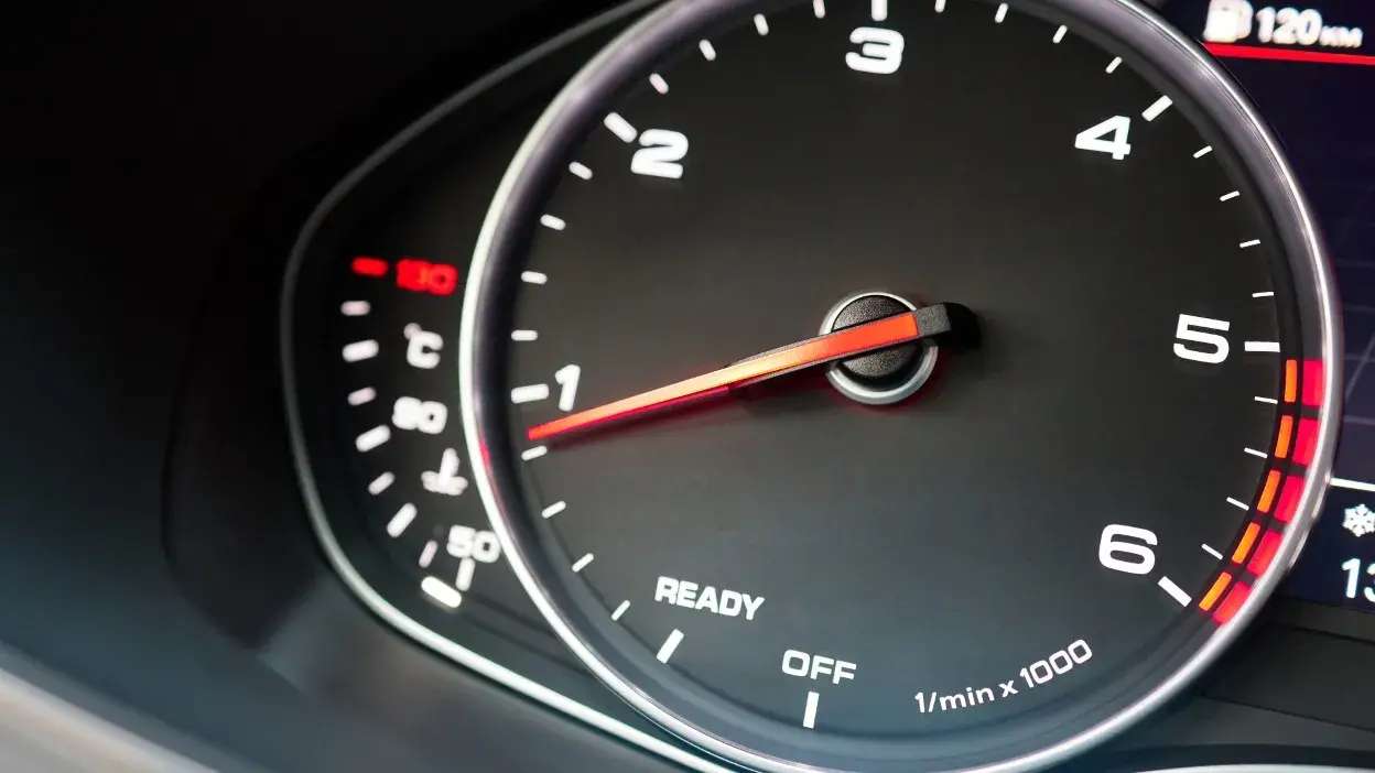 Contador de rotações de um automóvel com ponteiro a indicar cerca de 1.000 rpm.