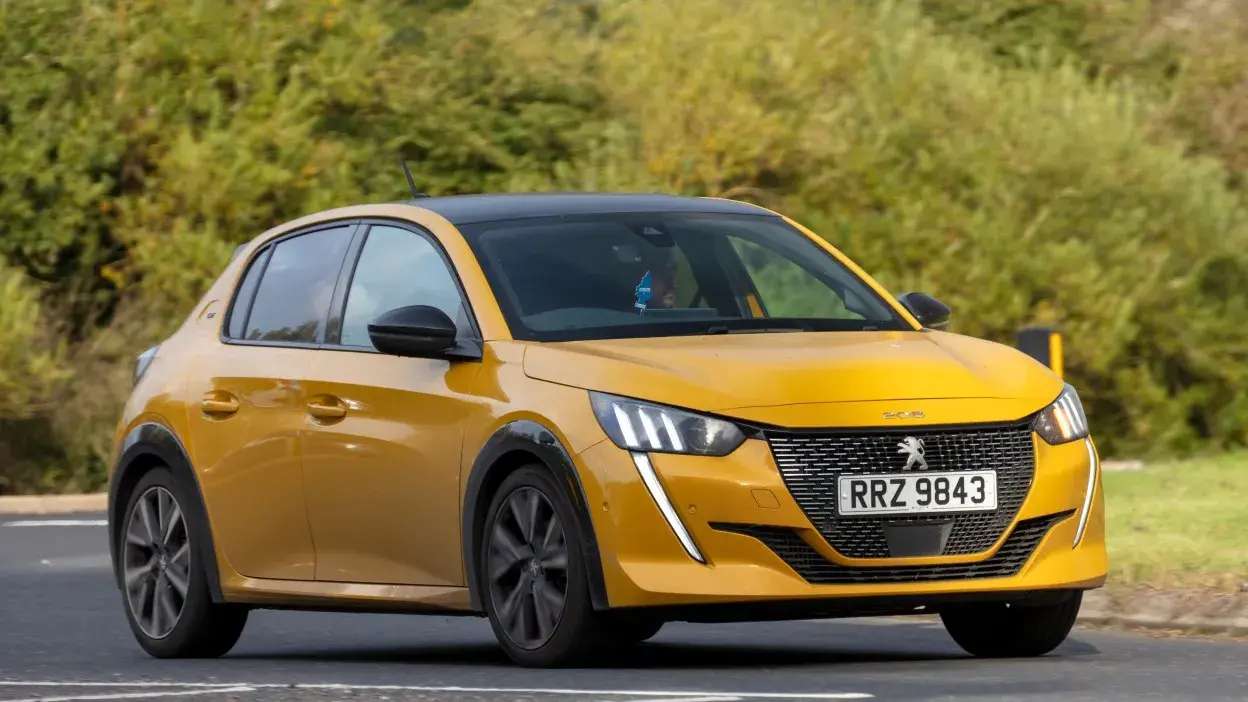 Carro Peugeot 208 amarelo a circular numa estrada com vegetação ao fundo.