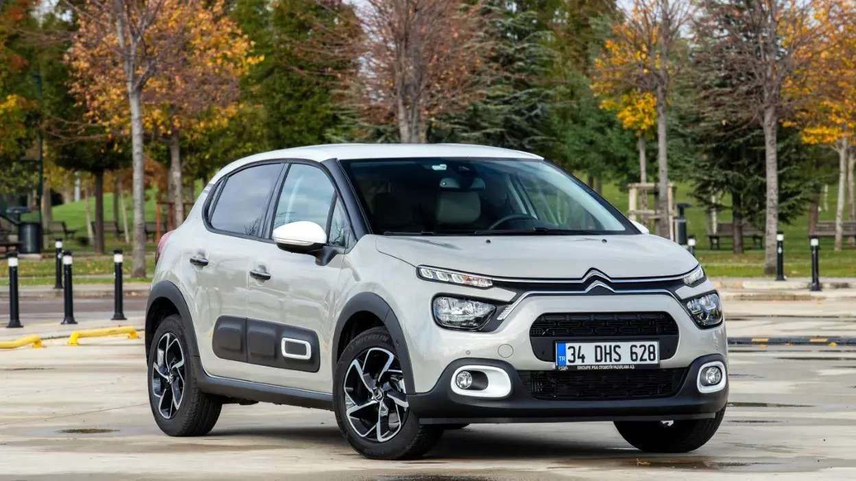 Automóvel Citroën C3 branco estacionado em parque com árvores outonais ao fundo