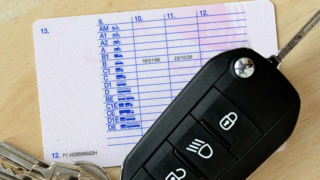 Carta de condução portuguesa com categorias visíveis e chave de carro preta em cima.