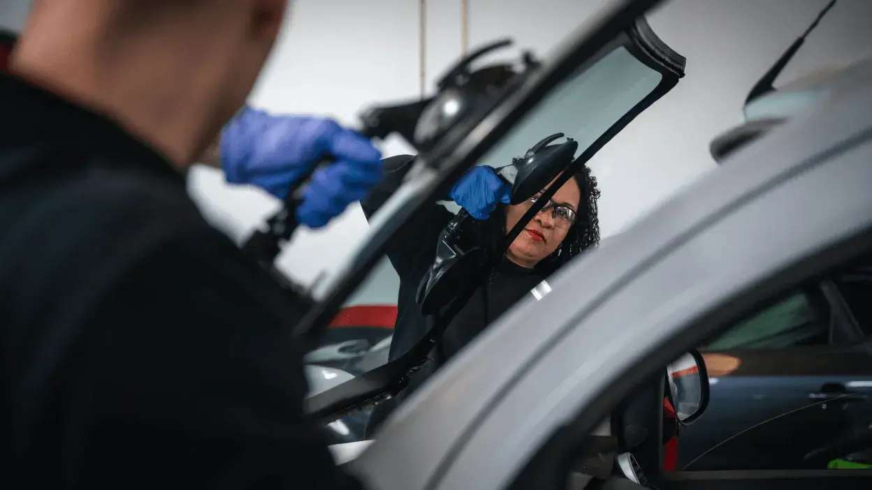 Técnica a instalar um para-brisas num automóvel com equipamento de sucção.