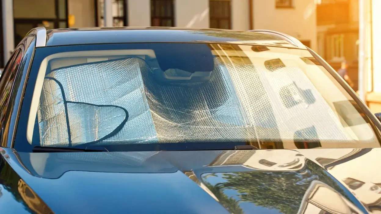 Tapa sol refletor colocado no interior do para-brisas de um carro estacionado ao sol.
