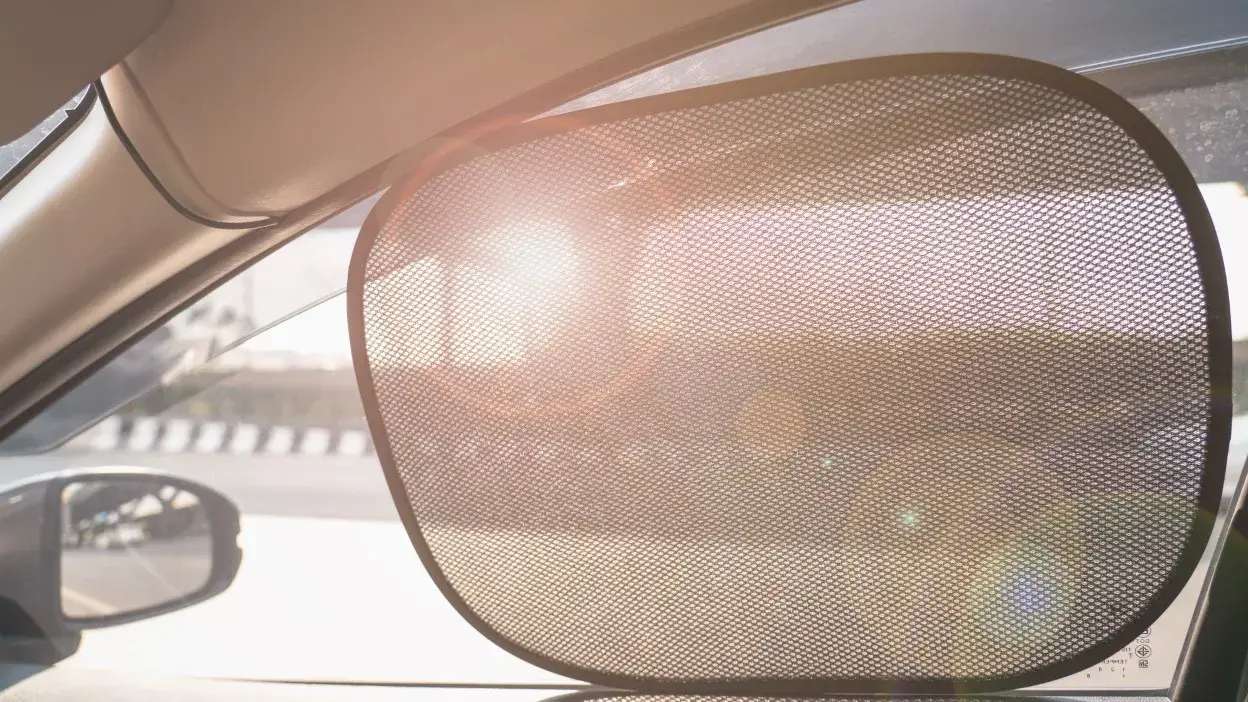 Tapa sol de malha colocado na janela lateral de um carro para bloquear a luz solar.