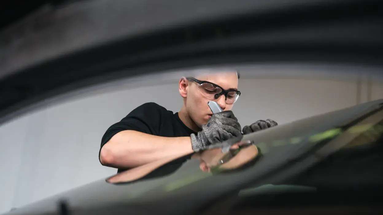 Especialista em vidro automóvel a reparar um para-brisas