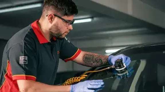 Técnico Carglass a fazer uma reparação rápida no vidro para-brisas de um carro