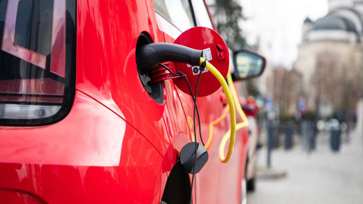 Carro elétrico vermelho ligado ao carregador, a ser carregado