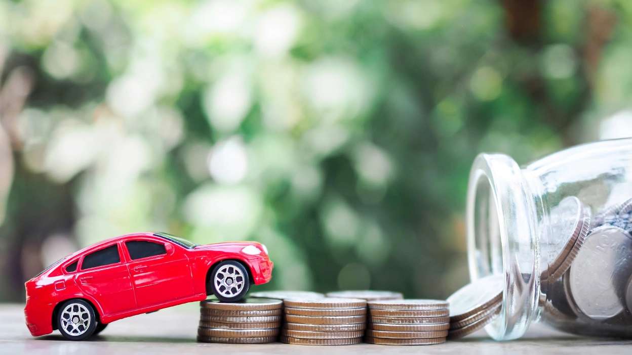 carro vermelho de brincar a subir lombas constituídas por moedas para relacionar com poupança