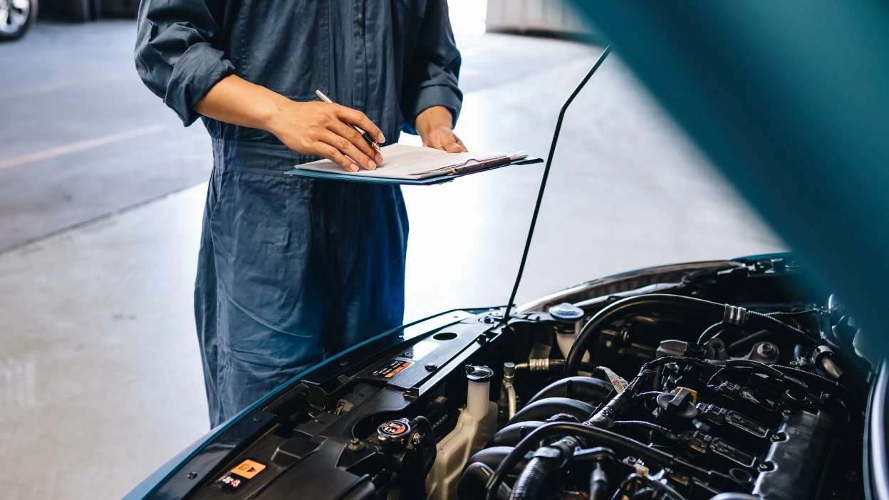 capô do carro levantando enquanto mecânico faz revisão e analisa o motor