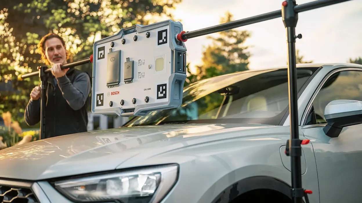 técnico da carglass a fazer a calibralão adas com máquina a um veículo