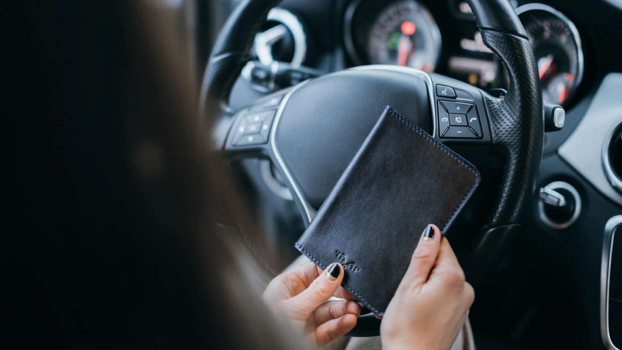 foto aproximada de uma mulher a segurar um porta documentos enquanto está sentada ao volante