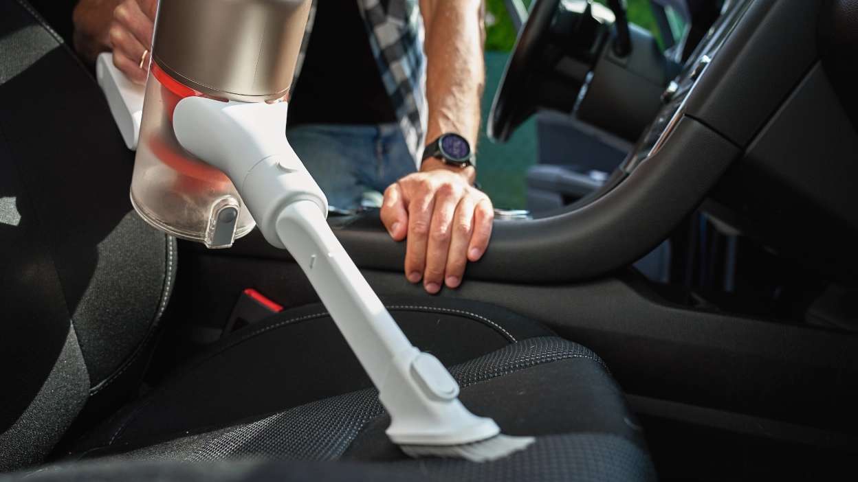 close up de pessoa a aspirar os bancos do carro