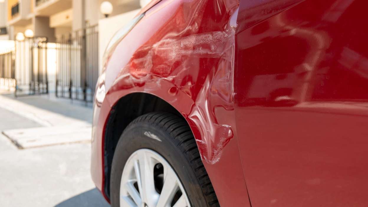 carro vermelho amolgado na lateral devido a acidente