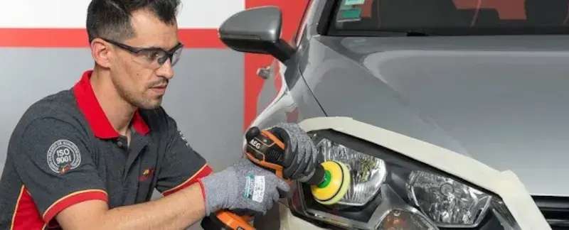 Técnico Carglass a polir um farol de um carro com uma máquina polidora