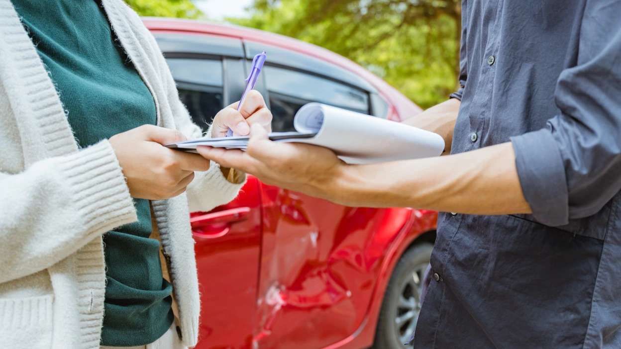 Dois senhores a preencherem documentos após acidente de carro