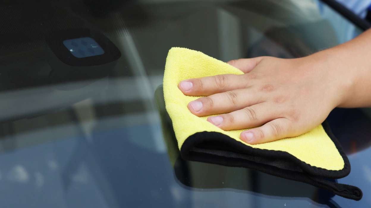 mão de pessoa a limpar vidro do carro